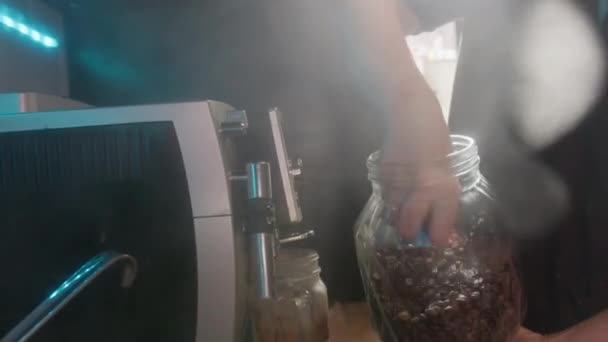 女性は瓶からコーヒー豆でコーヒーメーカーを満たし 台所で蒸気が上がる — ストック動画