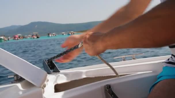 船上的一个人把锚从水里拖了出来 紧紧地抓住铁链 清晰地看到了大海和背景中的海岸线 — 图库视频影像