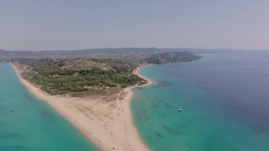 İnsansız hava aracı, Possidi Burnu, Halkidiki, Yunanistan üzerinde geriye doğru hareket ederek, kum yığınını, turkuaz denizi ve çevresini çevreleyen orman alanını gösteriyor.