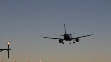 Uçak alacakaranlıkta ışıklar açıkken piste doğru iniyor - panorama aşağı eğimli