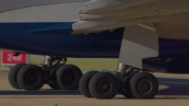 Pistte birden fazla tekerleği olan büyük bir uçağın iniş takımının yakın çekimi.