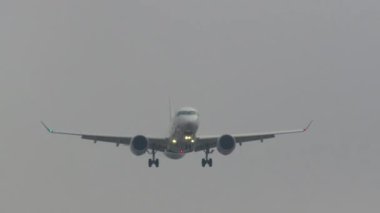 Gri gökyüzüne inmeye hazırlanan seyrüsefer ışıklarıyla aydınlatılmış bir uçak.