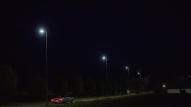 Geceleri, sokak lambaları, hareket halindeki bir trenin kırmızı ışıklarının göründüğü ve evlerin belli belirsiz çizgilerinin görülebildiği bir bölümü aydınlatıyor.