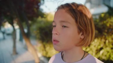 Açık havada plastik bir su şişesinden içen bir gencin yakın çekimi.