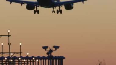 İniş takımlı uçak alacakaranlıkta pist ışıklarının yakınına kadar uzanıyor.