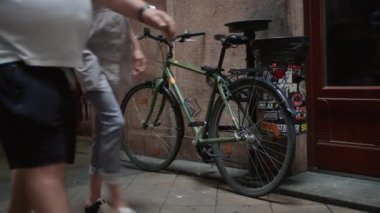 Bisikletle kaldırım taşı bir sokakta duvara yaslanmış ve arka planda bir çöp kutusu ve bina girişi var. Budapeşte, Macaristan