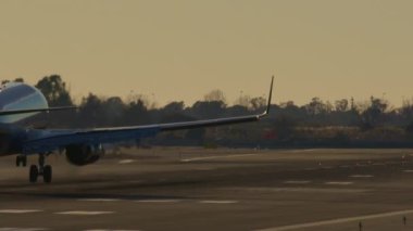 Pistte dumanla yere inen bir uçağın yavaş çekim görüntüsü.