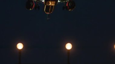 Uçak yaklaşıyor, iniş takımları açıldı, pist ışıkları görünüyor, gece gökyüzünün arka planı...