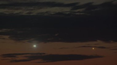 Akşam gökyüzüne yaklaşan uçaklardan gelen üç set iniş ışığı görüntülenir. Her bir ışık demeti, kara bulutların arkaplanına ve kaybolan ışığa karşı farklı mesafelerde yanar.
