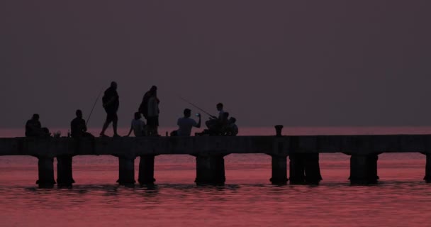 パーシー グリーク ジュリエル26 2023 コンクリートの桟橋で釣りやカジュアルな活動に従事している個人 反射する夕日 — ストック動画