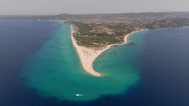 ギリシャのハラキキ岬に向かってドローンヘッド ターコイズ水の間の砂丘を捉え 目覚めを作るボート — ストック動画