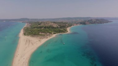 İnsansız hava aracı, Yunanistan 'ın Halkidiki kentindeki Possidi Burnu üzerinde ters yönde hareket ederek, turkuaz deniz ile birleşen kumlu bir plaj ve kıyı şeridinin uzaklığa çekildiğini gösteriyor.