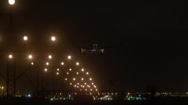 飛行機は ランウェイライトや街灯で距離を照らして夜空に向かって配置され 着陸装置が見えるように着陸するために近づく — ストック動画