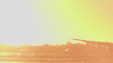 Uçak gün batımında arka ışık ve yanan motorlarla piste iniyor.