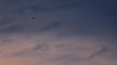 Uçak alacakaranlık gökyüzünün arka planına doğru hızla alçalıyor ve inişe hazırlanıyor.