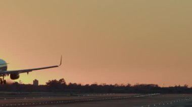 Aydınlatılmış piste alacakaranlık arkaplanı olan uçak iniyor.