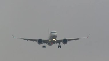 Gri gökyüzüne inmeye hazırlanan seyrüsefer ışıklarıyla aydınlatılmış bir uçak.