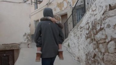 Bir abi, uyuyan küçük kız kardeşini dar bir sokakta taşır.
