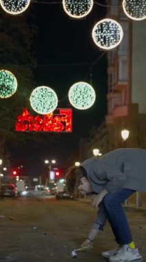 Şehir yolunda fenerlerle aydınlatılmış havai fişek ateşleyen genç bir çocuğu gösteren dikey bir video. Las Fallas, Valencia