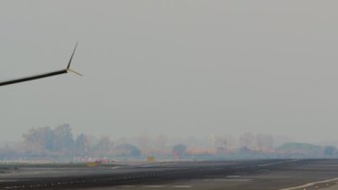 Uçak, havaalanındaki piste inerken lastik dumanı yaratıyor.