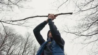 Kışın giydiği beyaz çocuk başının üstünde ağaçlarla ve bulutlu gökyüzüyle bir dal çeviriyor.