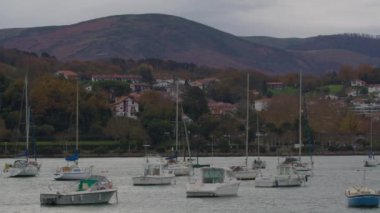 SAN SEBASTIAN, SPAIN - 3 HAZİRAN 2024: Bir limana demirlemiş çok sayıda yelkenli tekne ve önplanda tuhaf bir şehir