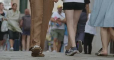 Şehir caddesinde yürüyen bir grup yayaydı. Çeşitli giyim tarzları ve ayakkabılar, çeşitli ve yoğun bir kentsel ortamı işaret ederek görülmektedir.
