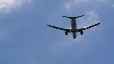 Kalkıştan sonra yukarı tırmanan bir uçağın telefoto görüntüsü, dağınık bulutlu açık mavi bir gökyüzüne karşı görülüyor.