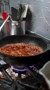 Profesyonel şef et ve sebze sosunu ağır iş tavasında azaltıyordu. Mutfak ortamında yoğun gaz alevinin üzerinde kaynıyordu.