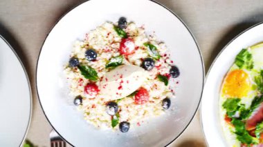 Yulaf lapası, yumurta, krep ve krep de dahil olmak üzere çeşitli Doğu Avrupa kahvaltı yemeklerinin tabakları bir masaya dizilerek görsel olarak çekici bir yayılma oluşturulmuştur.