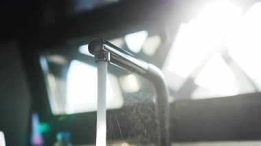 Pürüzsüz krom musluktan dökülen saf su modern banyo tasarımını doğal ışık ve temiz, ferahlatıcı estetik bir şekilde ön plana çıkarıyor.