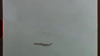 Süper 8 filmde çekildi. Bulutlu bir gökyüzünde uçan uçak. Retro 8mm ya da süper 8 film efekti ve ışık sızıntısı nostaljik ve klasik bir estetik yaratıyor.