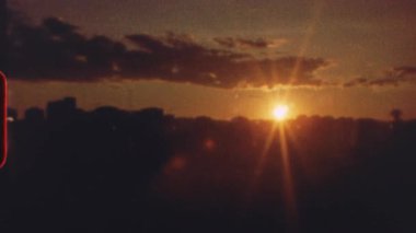 8 mm 'lik film - canlı turuncu ve sarı günbatımı Metropolitan ufuk çizgisinde sıcak bir parıltı yaratıyor, nostaljik ışık sızıntısı efekti klasik estetik ve sakin kentsel atmosfer yaratıyor
