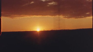 8 mm 'lik film - sıcak turuncu ve kırmızı renkler batan güneşin altı ayrı çekimine hakim olurken, manzara siluetleri ve şehir yapıları ön planda görülebilir.