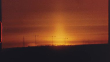 8 mm 'lik film - sıcak turuncu ve kırmızı renkler batan güneşin altı ayrı çekimine hakim olurken, manzara siluetleri ve şehir yapıları ön planda görülebilir.
