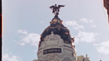 MADRID, SPAIN - 21 Temmuz 2025: İspanya 'nın Madrid kentindeki Metropolis Binası' nın tepesinde berrak mavi gökyüzü ve minimal bulutlarla zenginliğin ve ilerlemenin sembolü olan kanatlı zafer heykeli duruyor