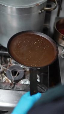 Profesyonel şef, ısıtılmış ızgarada ince krep hamuru yayıyor ve paslanmaz çelik mutfak ortamında hassas Fransız mutfağı uzmanlığı yapıyor.