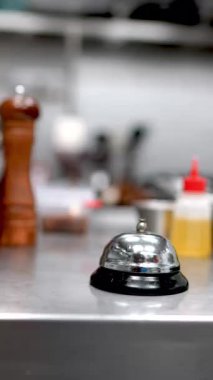 Parlayan mutfak tezgahında koruyucu eldiven takan profesyonel bir el. Mutfak tezgahında çalan metal yüzey tamamlanmış siparişin canlı sinyalini yansıtıyor. Ya da acil mutfak isteği.