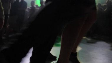 İnsanlar yeşil ışıkları ve bulanık arka planı olan karanlık kulüp zemininde dans ediyorlar.