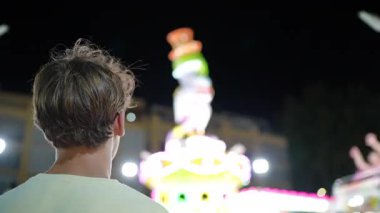 Kısa saçlı çocuk, gece vakti eğlence parkına giderken arkadan çekilmiş.