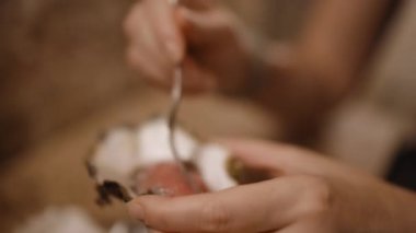 Yumuşak ışıkta çiğ kabuklu deniz ürünleri yerken ellerinizi tutun ve çatal ve istiridye tutun.