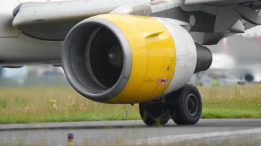 Pistte sarı kaplaması ve tekerleği olan bir uçak motorunun yakın görüntüsü, mühendislik ayrıntıları ve havacılık mekaniği vurgulanıyor