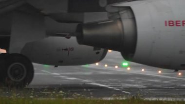 SAN SEBASTIAN, SPAIN - 1 AĞUSTOS 2025: San Sebastian Havalimanı 'nda yağmurlu havalarda taksicilik yapan İberya Airbus A320' nin motorunun ve iniş takımlarının yakın görüntüsü