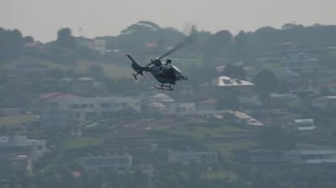 Gijon, İspanya - 27 Temmuz 2025: Hava operasyonları sırasında Gijon 'daki yüksek binaların yanından bir Sivil Korumalı helikopter geçiyor. Uçak, büyük yaz etkinliklerinde kamu güvenliği görevlerini destekler.