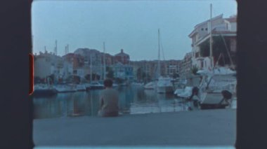 Küçük bir sahil kasabasında marinada tek başına oturan genç çocuk eski moda süper 8 mm 'lik bir filmle yakalandı.