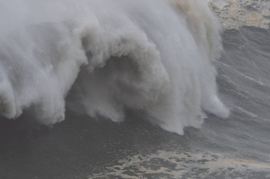 Büyük bir okyanus dalgası, Portekiz, Nazare 'de kayalık kıyılara çarpıyor. Efsanevi büyük dalga sörf merkezi.