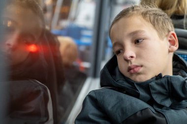 Düşünceli öğrenci otobüsün camından dışarı bakıyor, okula günlük gidip gelişi sırasında dalgın dalgın dalgın, ilerideki yolculuğu yansıtıyor.