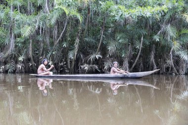 Huaorani kabilesinden Huaorani erkekleri Ekvador 'un Amazon bölgesindeki ormanlarda ahşap kanoda balık tutuyorlar.