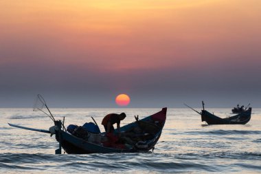 Balıkçı ve tekneleri denizde kumsalda
