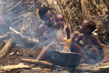 Baka kabilesinden pigme anne ve çocukları Kamerun ormanında ateşin yanında. Doğada bir günlük aile hayatı..